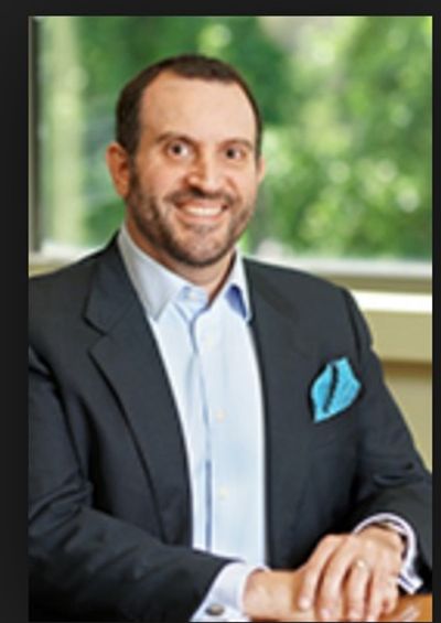 Man in a suit smiling at the camera indoors.